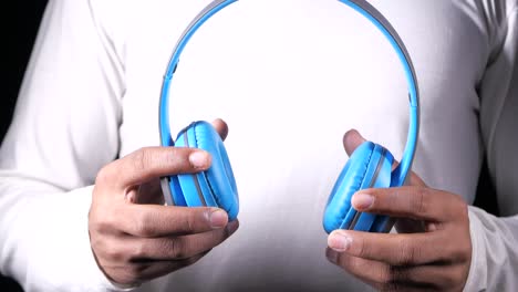 person holding blue over-ear headphones