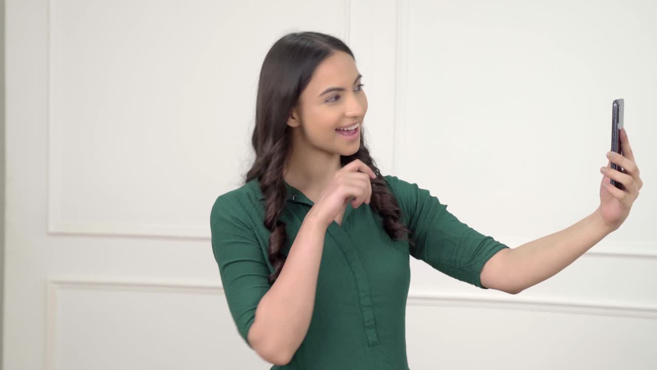 mujer india haciendo clic en selfies usando móvil