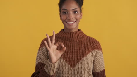 una mujer sonriente dando una señal de ok.