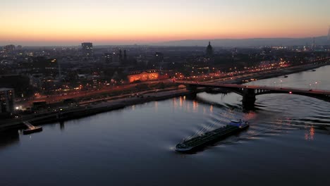 mainz with an aerial drone view at magic hour showing the city with lights and a ship on the rhine river