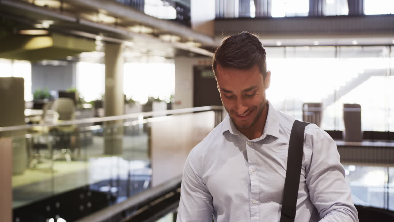 Smiling businessman in office building, carrying bag and looking down