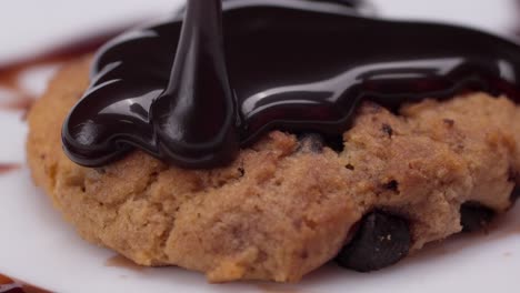 slow motion macro shot of rich chocolate poured over a freshly baked cookie