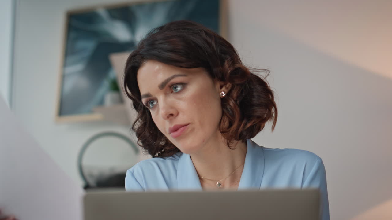 Thoughtful lady working computer reading documents at workdesk office closeup
