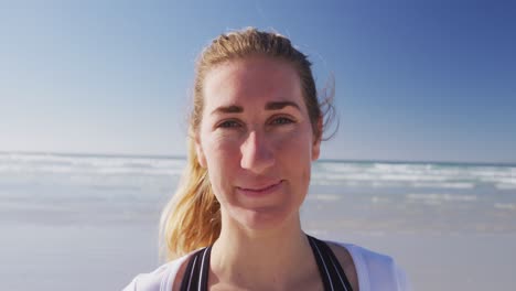 caucasian woman looking at camera and smiling on the beach and blue sky background