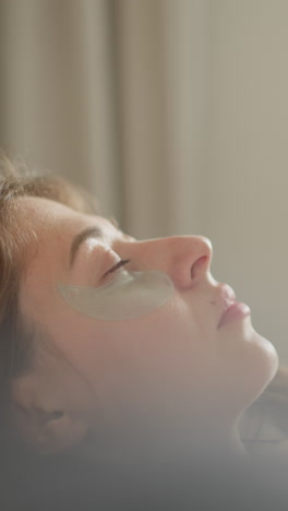 스파 치료 후 시간을 즐기는 갈색 여성은 침대에 누워있는 눈을 닫고 편안한 표정과 평온한 감정으로 베개에 누워 있습니다.