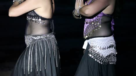 two women performing a belly dance at night
