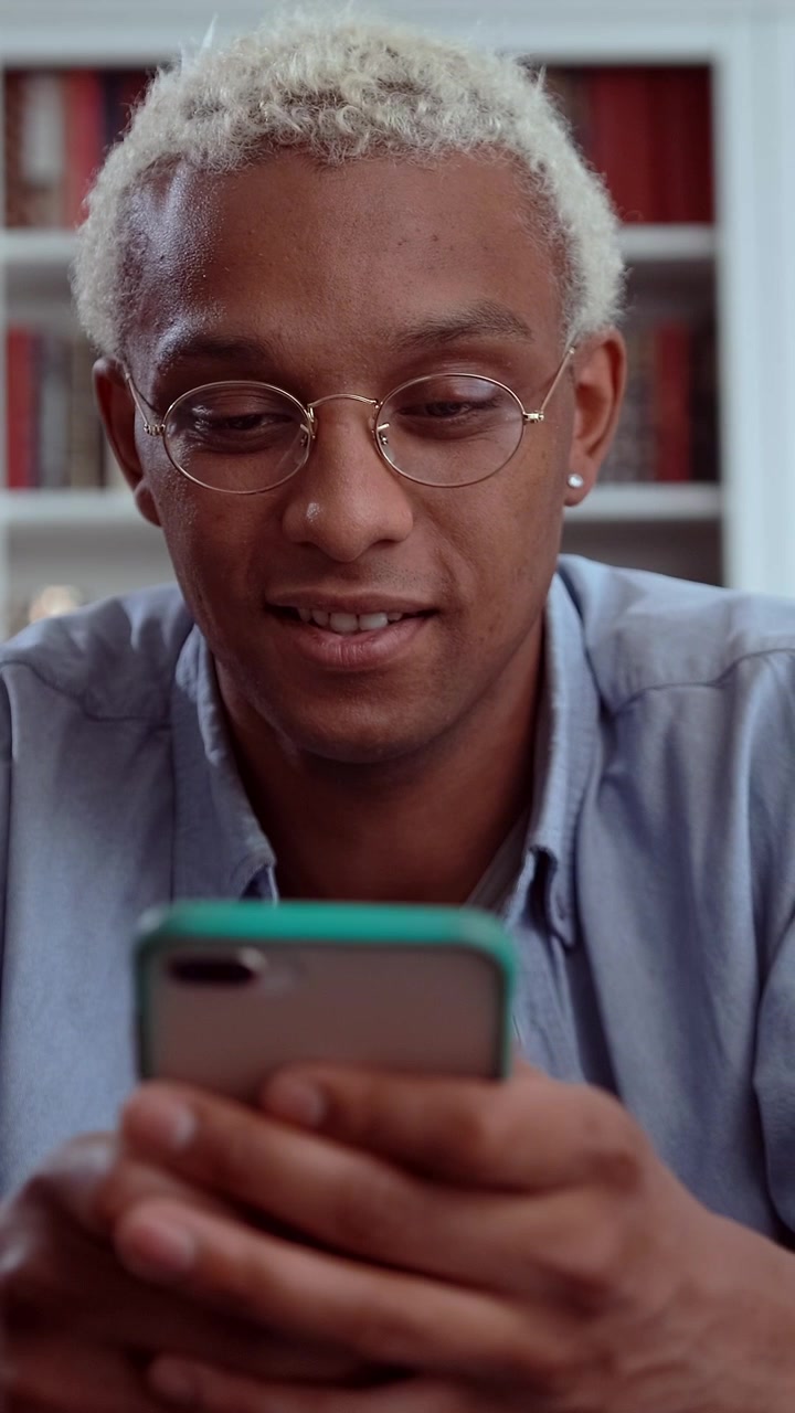 Happy african american man with round glasses smiling warmly while looking down