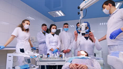 setting the medical dentistry equipment above the patient. showing the group of students the work of microscope.