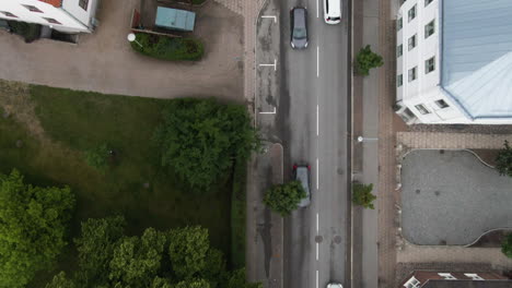 Narrow-suburbs-street-with-moving-vehicles,-top-down-aerial-view