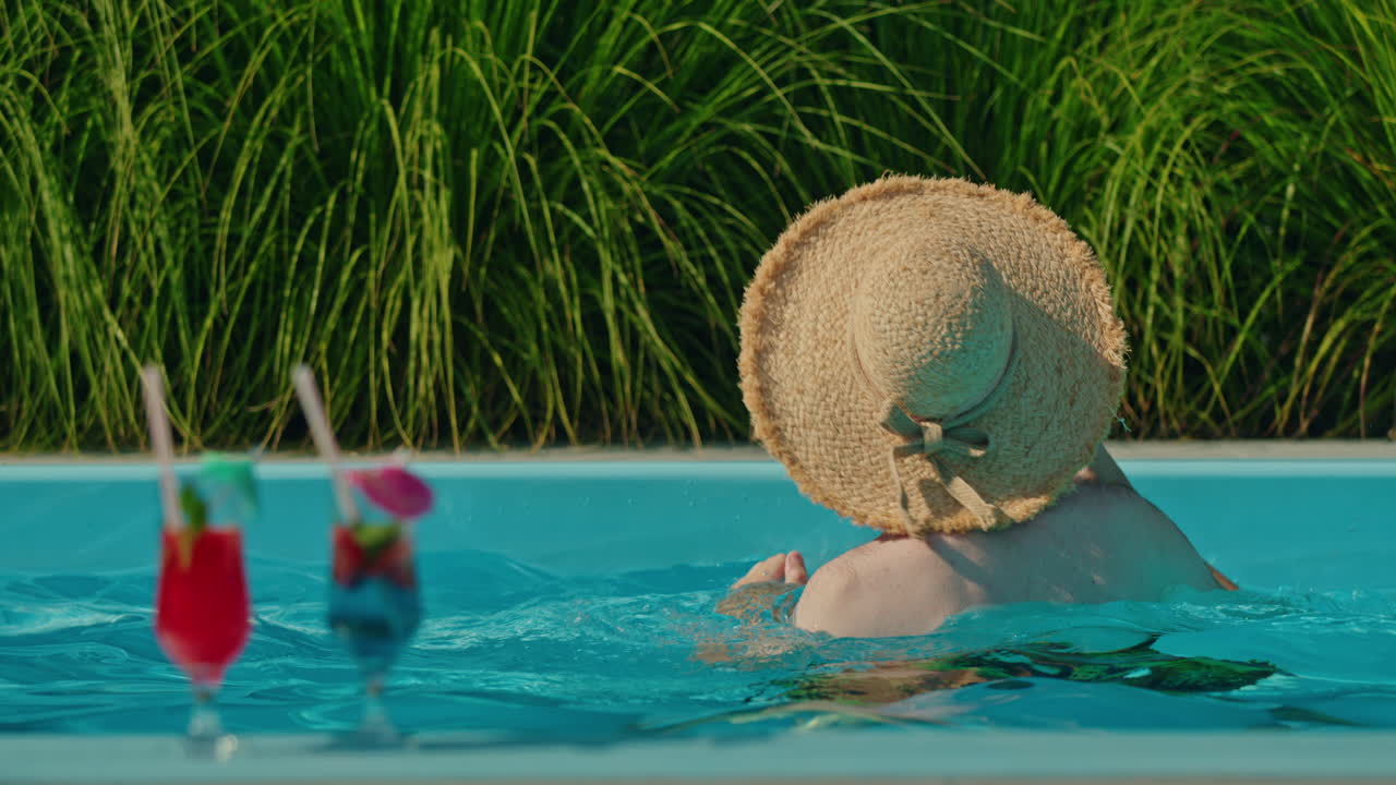 Man Swimming in Pool with Cocktails
