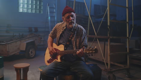 elderly man playing guitar in an abandoned warehouse