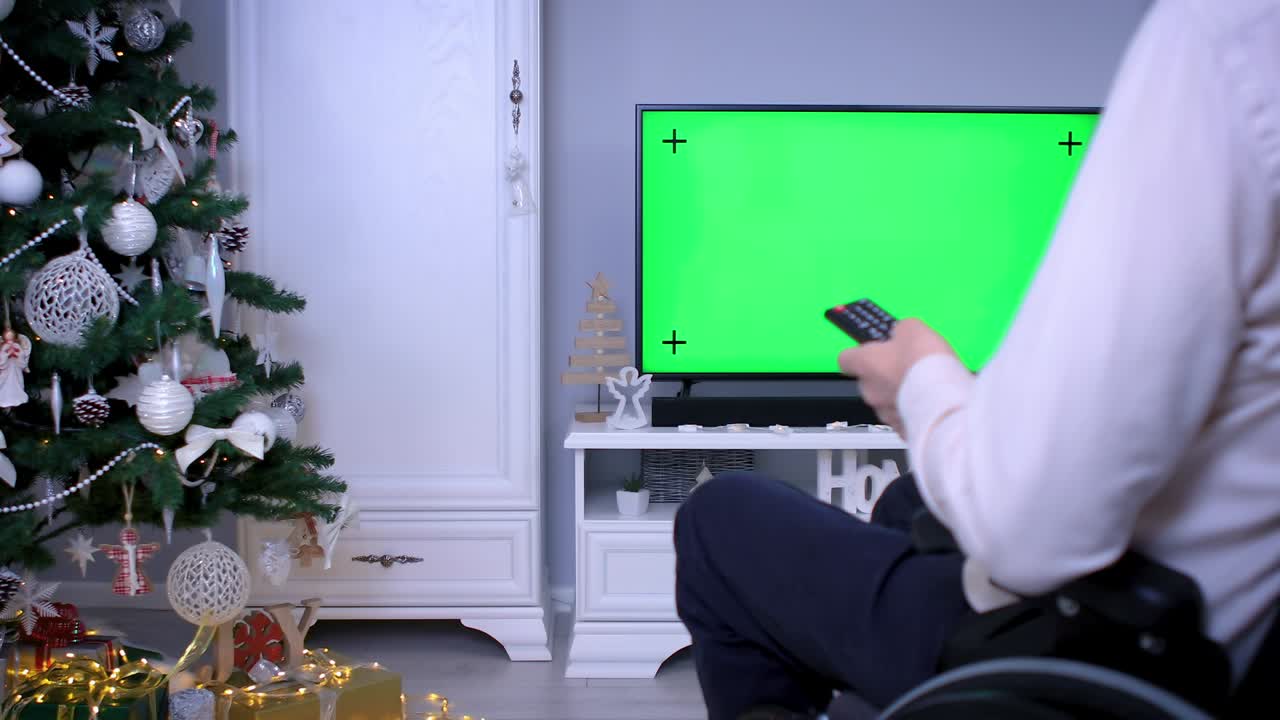 Man in wheelchair watching tv green screen on Christmas
