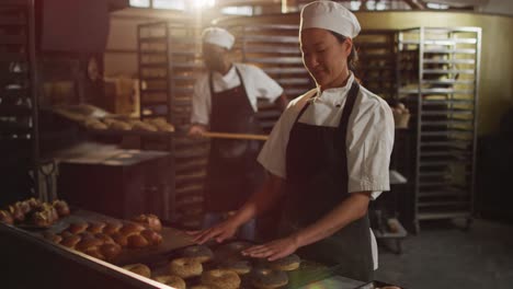 Animation-Einer-Glücklichen-Asiatischen-Bäckerin,-Die-Croissants-Auf-Einem-Tablett-Anordnet