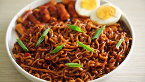 jjajang rabokki - fideos instantáneos coreanos o ramyeon con pastel de arroz coreano o tteokbokki y huevo en salsa de frijol negro - estilo de comida coreana