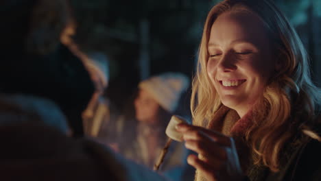 camping woman eating marshmallow chatting to man having conversation smiling sitting by campfire 4k