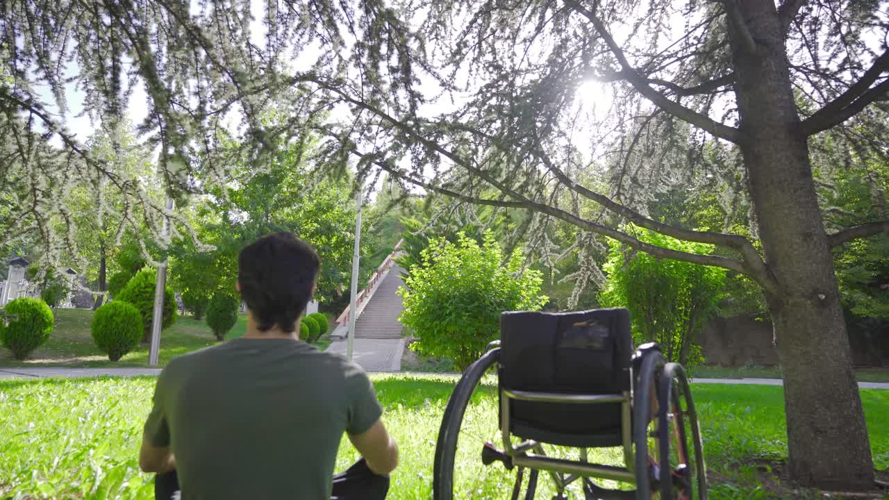 장애인 젊은이가  ⁇ 체어를 사랑스럽게 쳐다보고 있습니다.