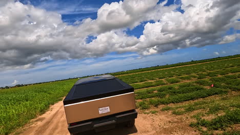 futuristic tesla cybertruck ride outdoors on sunny day. fpv drone following the automobile in the field.