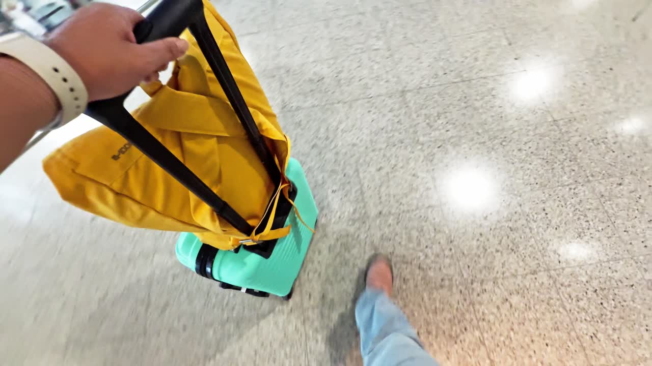 Hand Holding Suitcase Handle and Yellow Bag in Airport