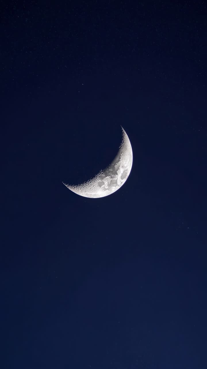 A serene night sky with a crescent moon captured from a low-angle shot, evoking a tranquil