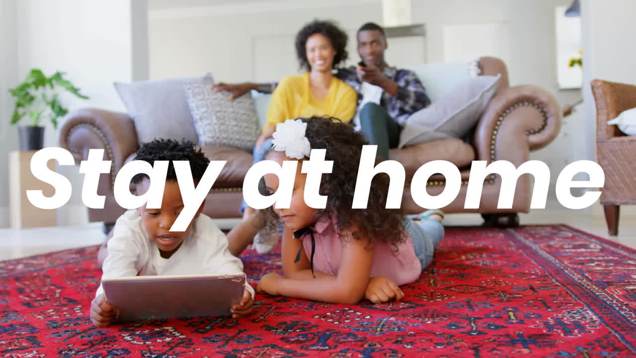 Animation of stay at home text over parents with sister and brother using tablet at home