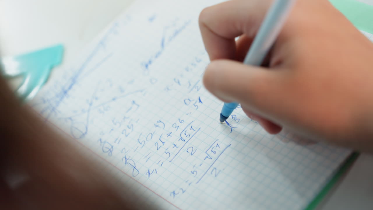 student taking quick notes in notebook, closeup of hurried female hand writing blue ink beside turquoise protractor, blurred motion and sketching of formulas, focused tension during exam rehearsal