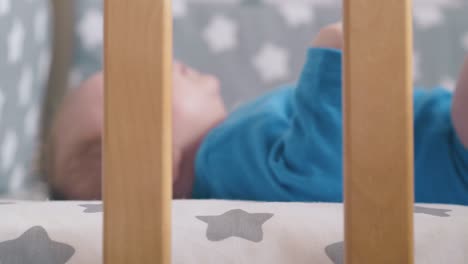 funny child with blue eyes rests in cot with decorated linen