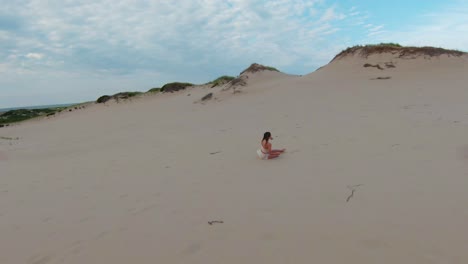 a bird's eye view of the desert landscape and following a girl running on the high sand dunes and trails in the dune shacks trail in provincetown, cape cod, massachusetts