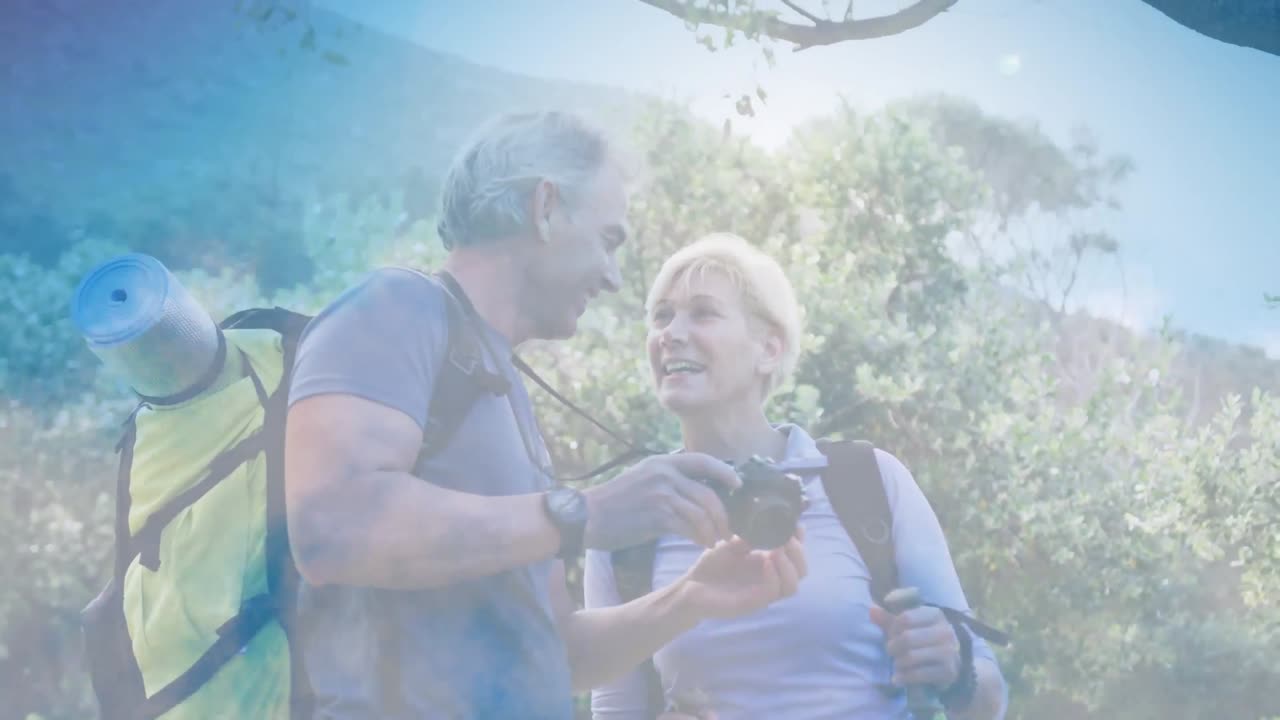 feliz pareja caucásica de alto nivel haciendo senderismo tomando fotos en las montañas sobre nubes en movimiento