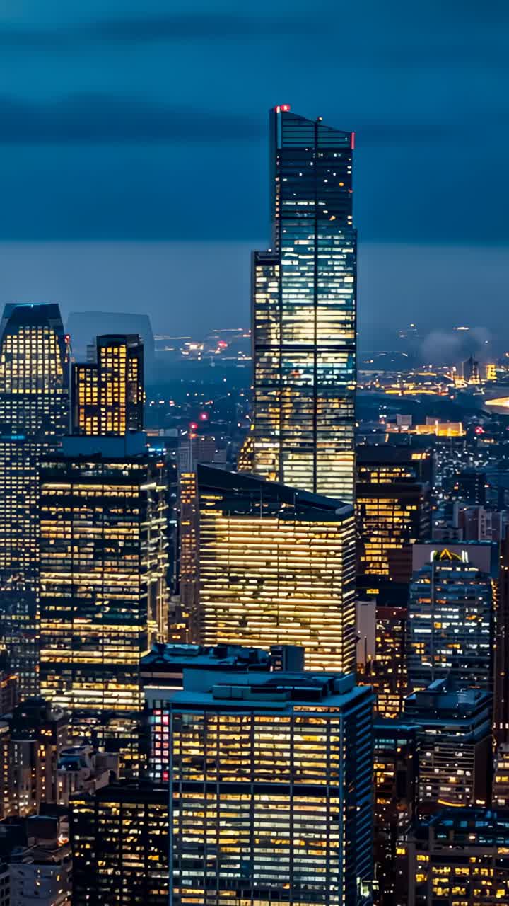 Vertical video: Camera capturing city skyline at dusk, with illuminated glass tower and city lights