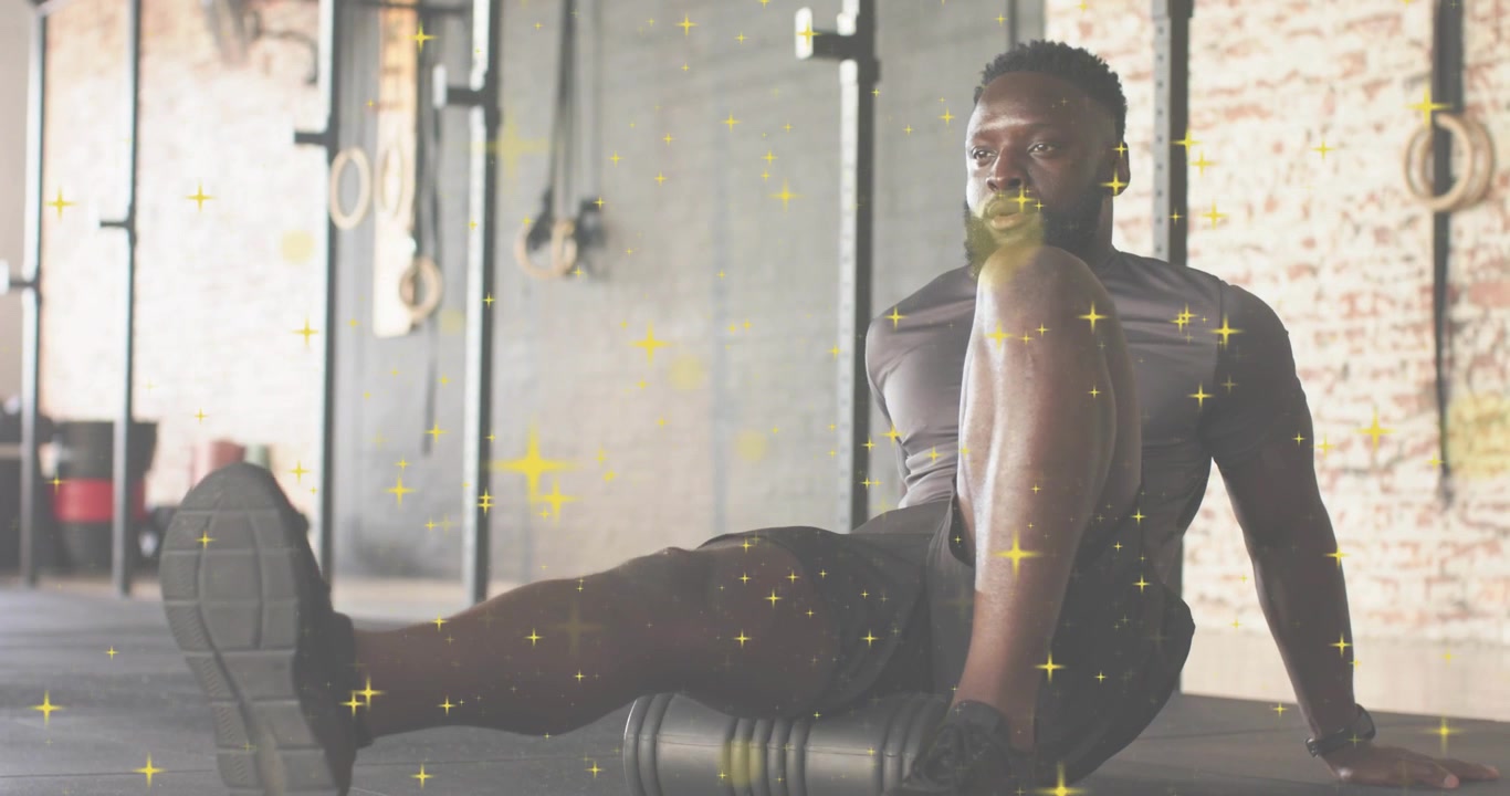 Atleta fitness che utilizza un foam roller per il massaggio dei muscoli posteriori della coscia per il sollievo, con sovrapposizione di scintille dorate.