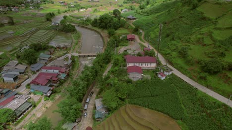 Fliegen-Durch-Ein-Kleines-Dorf-Zwischen-Den-Hügeln-Und-Dem-Fluss-Im-Gedämpften-Licht