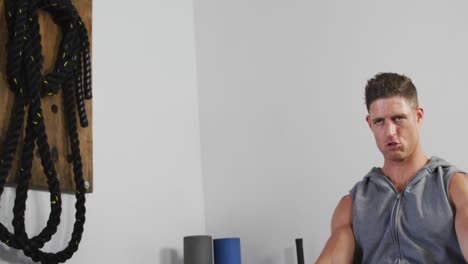 fit tired caucasian man exercising, practicing rowing inside gym