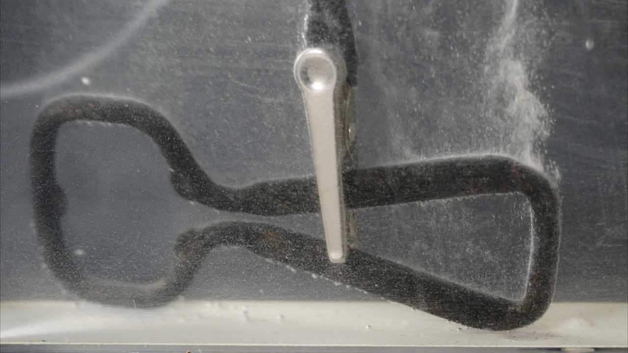 Rusted bottle opener is cleaned by electrolysis in time-lapse motion