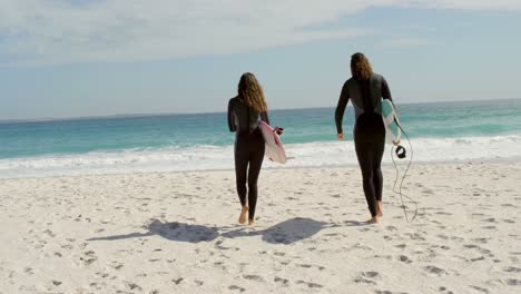 pareja caminando con tabla de surf en la playa 4k