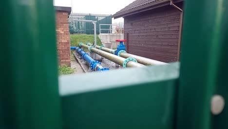 british water supply industrial distribution pipeline at utilities substation secured behind metal fence