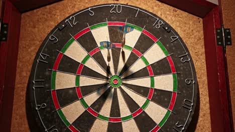 Three-darts-hitting-7-points-on-a-dart-board-that-hangs-in-front-of-a-cork-wall