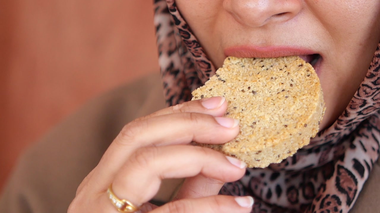 Close-up of a Woman Eating a Seeded Cookie