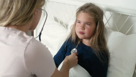 pediatra examinando los pulmones de una niña enferma en la cama