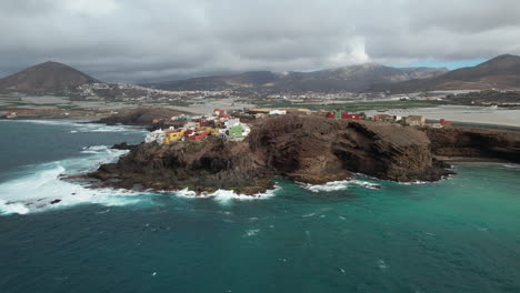 wonderful aerial shot in orbit in the place known as punta de galdar and in the background the mountain of galdar and the houses built on the coast