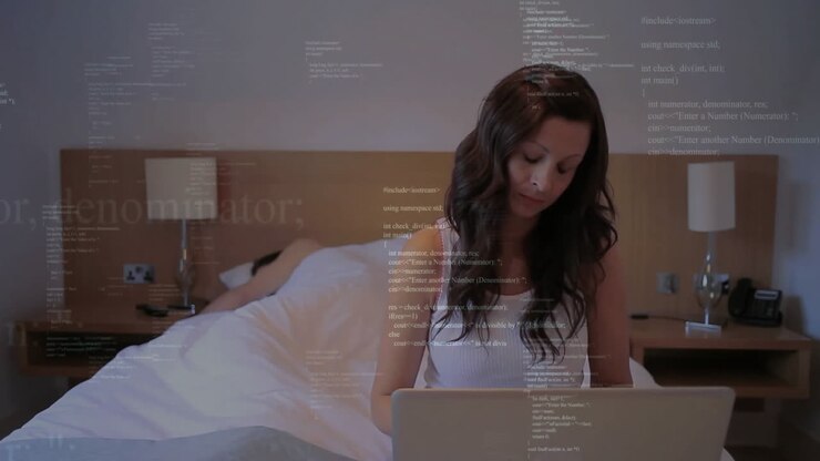 Using laptop in bedroom, woman with programming code animation on screen