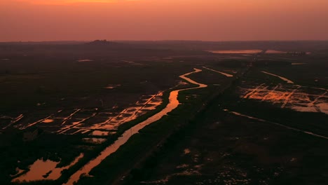 orange sky during sunset over paddy fields and creek near vasai in mumbai city, india