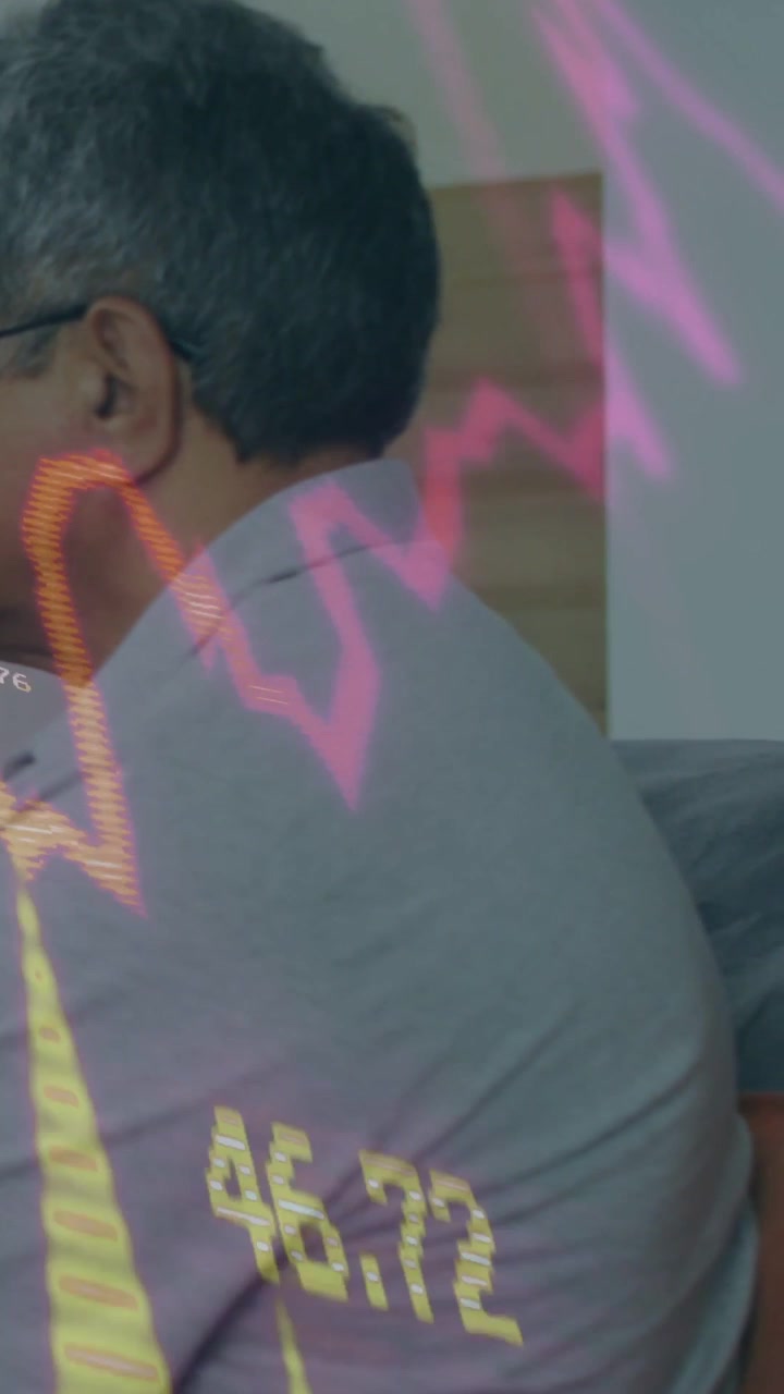 Video verticale: Uomo anziano seduto sul divano, con una forma d'onda che compare e fa apparire numeri per la tecnologia.