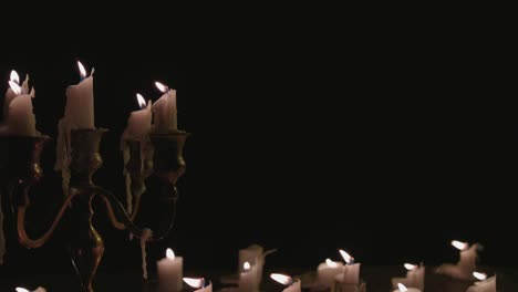 a group of white candles some on a candelabra lit up and running for a while