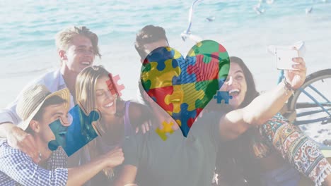 animation of colourful puzzle pieces heart and autism text over happy friends at summer beach party