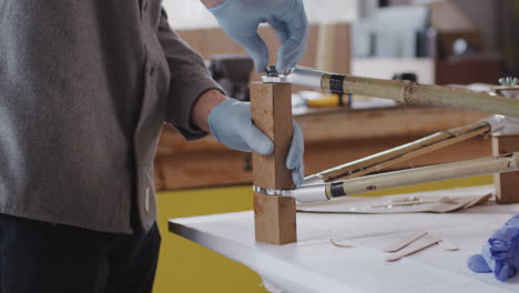 close up of male craftsman in workshop assembling hand built sustainable bamboo bicycle frame