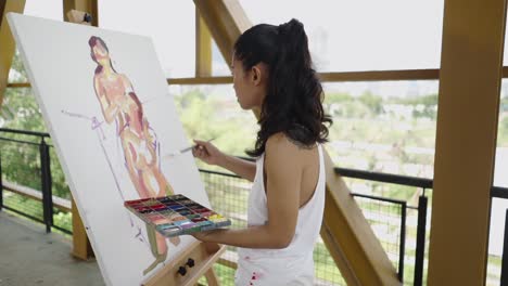woman painting a figure on canvas outdoors