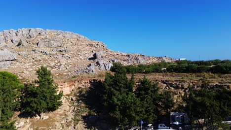 Pueblo-De-Lindos-En-Rodas,-Grecia-Con-La-Acrópolis-De-Lindos,-Casas-Y-El-Mar-Mediterráneo-Durante-El-Día-Filmado-Con-El-Dron