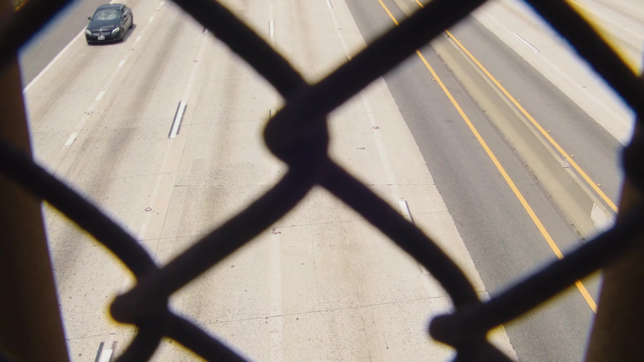 Panoramica del traffico autostradale di Los Angeles, molteplici corsie di auto, giorno soleggiato e luminoso.