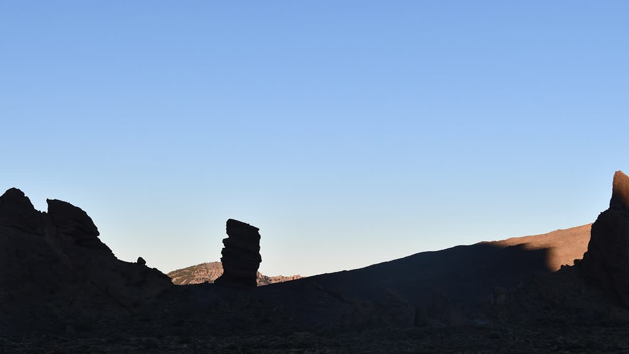 un timelapse captura la luz temprana del amanecer iluminando gradualmente roque cinchado y rocas garcía en el parque nacional del teide, tenerife