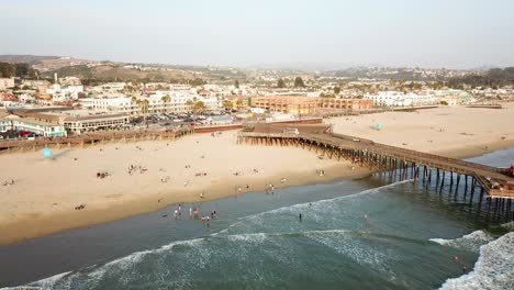 Gente-En-Pismo-Beach-Al-Lado-Del-Muelle-De-Madera,-California